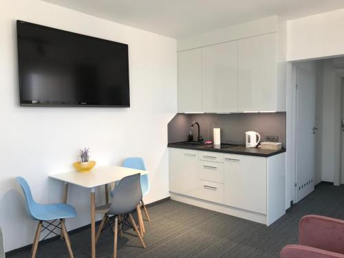 eine Küche mit weißen Schränken sowie einem Tisch und Stühlen in der Unterkunft Apartament 215 Planeta 2-pokojowy z balkonem in Mielno