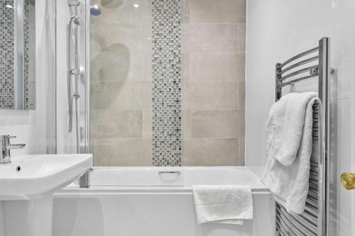 ein weißes Badezimmer mit einem Waschbecken und einer Badewanne in der Unterkunft Abbey Sands Hotel in Torquay