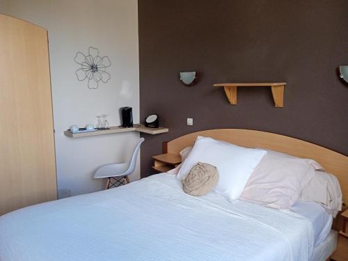 um quarto com uma cama com almofadas brancas em Hotel de la Gare em Noyers-sur-Cher