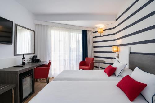 a hotel room with two beds and a desk at Medplaya Hotel Riudor - Adults Recommended in Benidorm