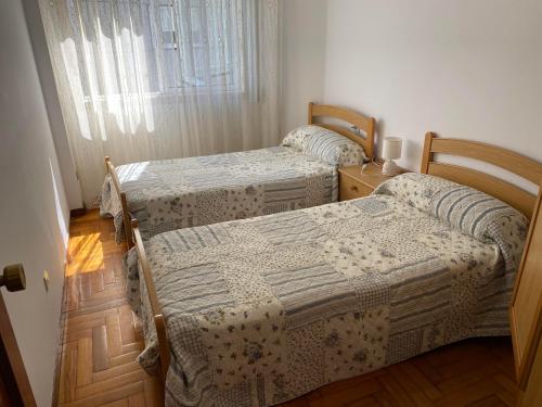dwa łóżka w pokoju z oknem w obiekcie MAR DE BAIONA w mieście Baiona