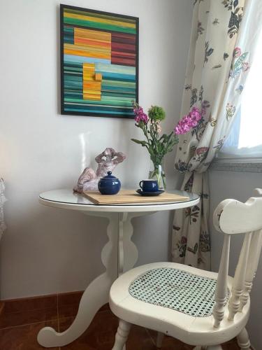 a table and a chair with a vase of flowers and a painting at Fairview in Sabardes