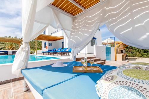 a pool villa with a bed and a table and chairs at White Blue Villa in Lachania