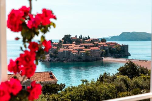a view of a town on the water with red flowers at Sun Rose Apartments Sveti Stefan in Sveti Stefan