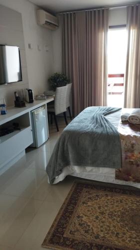 a bedroom with a bed and a desk with a television at Pousada das Seriemas in Pirenópolis