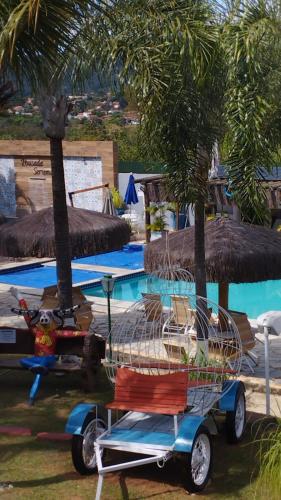 a golf cart parked next to a pool with palm trees at Pousada das Seriemas in Pirenópolis