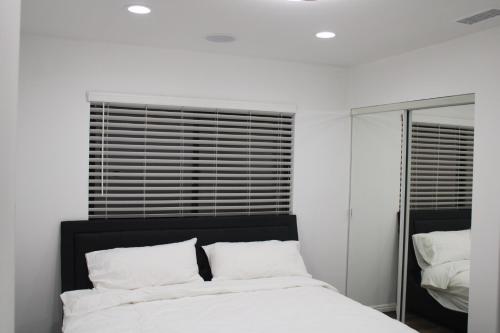 Habitación blanca con cama y espejo en Pearl Beach Villa Huntington Beach en Huntington Beach
