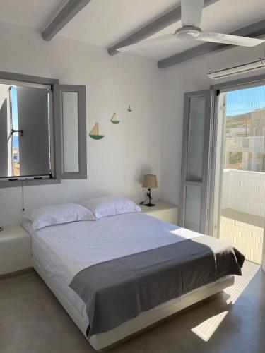 a white bedroom with a large bed and a window at Maganiotis Rooms in Kimolos