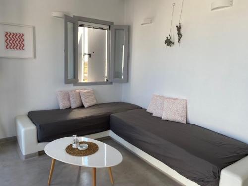 a room with two beds and a table and a window at Maganiotis Rooms in Kimolos