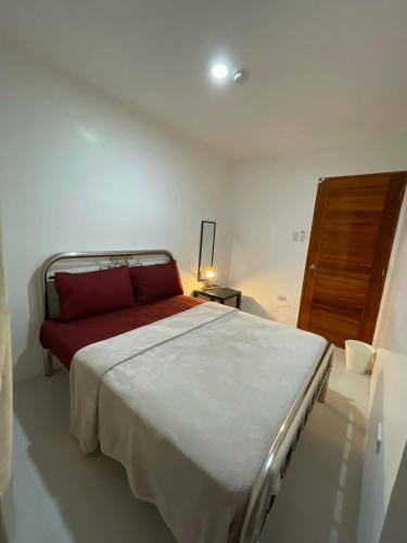 um quarto com uma cama grande e uma almofada vermelha em Sto. Niño Whole House w/ 2 AC Bedrooms em Lucena
