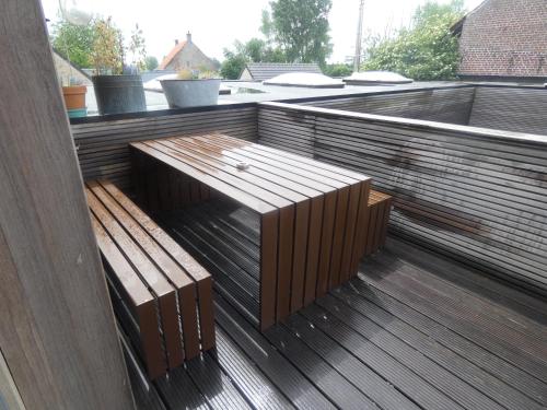 a wooden bench sitting on top of a deck at 't en lande in Alveringem