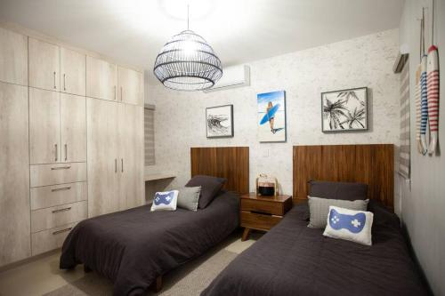 a bedroom with two beds and a chandelier at Casa Caracol. Cerca de la playa en residencial privado! in Mazatlán
