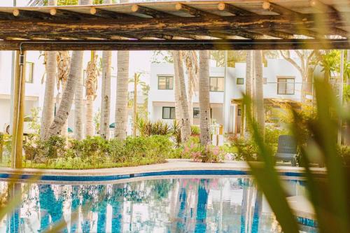 a swimming pool in front of a building with trees at Casa Caracol. Cerca de la playa en residencial privado! in Mazatlán
