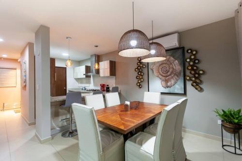 a dining room and kitchen with a wooden table and chairs at Casa Caracol. Cerca de la playa en residencial privado! in Mazatlán