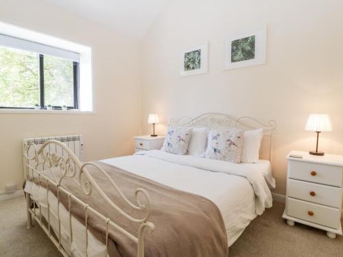 ein weißes Schlafzimmer mit einem weißen Bett und einem Fenster in der Unterkunft Swallow Cottage in Shaftesbury