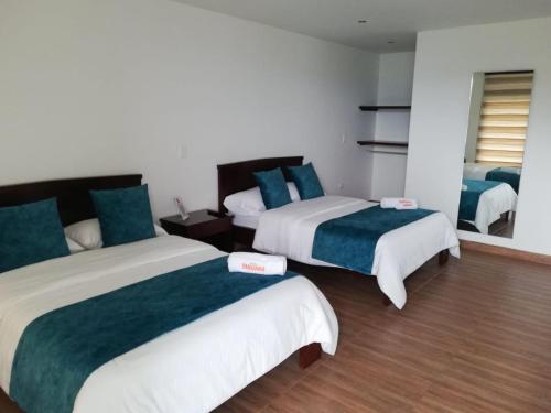 a hotel room with two beds with green and white sheets at Hotel Takuara in Vergara