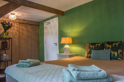 a bedroom with green walls and a bed with towels on it at Puur & Simpel, Buitengewoon vertoeven in de Brabantse Kempen in Westerhoven