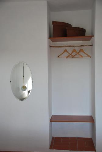 a room with a white wall with a mirror and a shelf at Monte Ramos in Ferreira do Alentejo