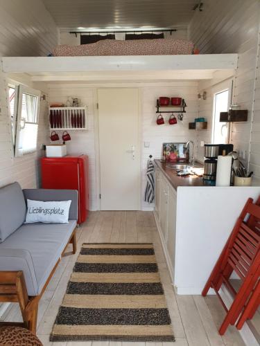 una cocina con sofá y mesa en una casa pequeña en Tiny House en Schönbeck