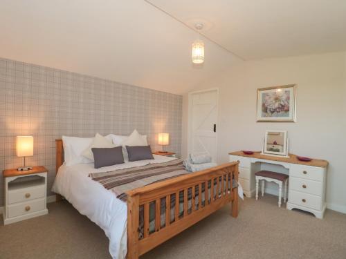 a bedroom with a large bed and a desk with a desk at Garden Cottage, Rode Farm in Frome