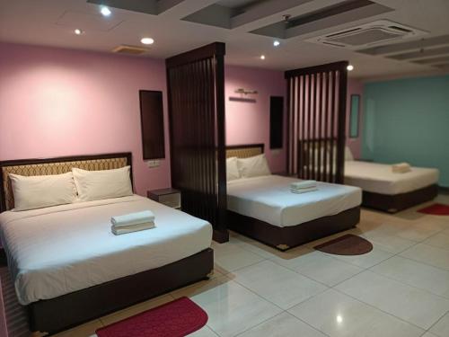 two beds in a room with pink walls at Hotel Sri Sutra PJ 222 in Petaling Jaya