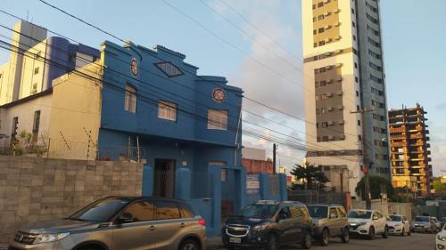 un groupe de voitures garées devant un bâtiment bleu dans l'établissement Pousada Cisne Branco, à Natal