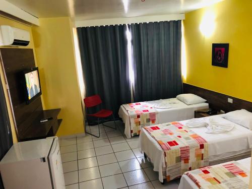 a hotel room with two beds and a television at Rede Andrade Plaza Recife in Recife