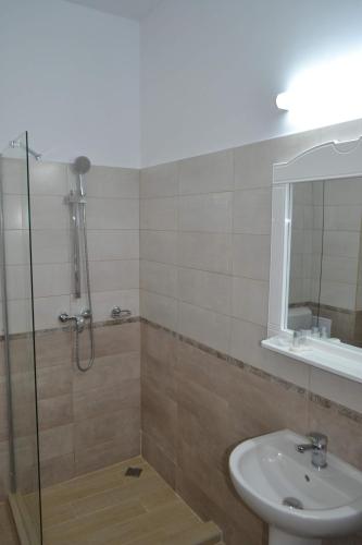 a bathroom with a shower and a sink and a mirror at Hotel Insula in Neptun