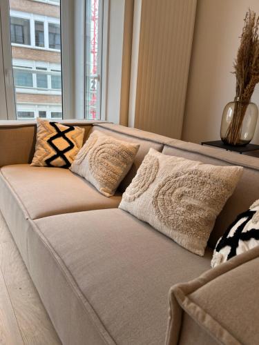 ein Sofa mit Kissen darauf im Wohnzimmer in der Unterkunft Chez Coceau - Luxery apartment with sea view in Ostende