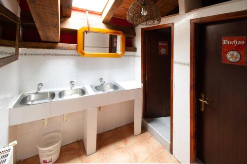 a bathroom with two sinks and a mirror at La Pata de Oca Hostal Rural y Albergue in Torres del Río