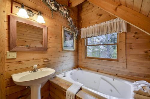 baño con bañera y lavamanos en una cabaña de madera en On Eagles Wings, en Pigeon Forge