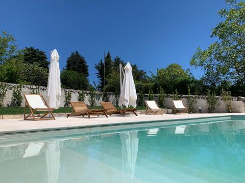 a group of chairs and umbrellas next to a swimming pool at Trulli d'Itria in Martina Franca