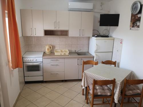 a small kitchen with a table and a white refrigerator at Apartments Govic in Zaboric