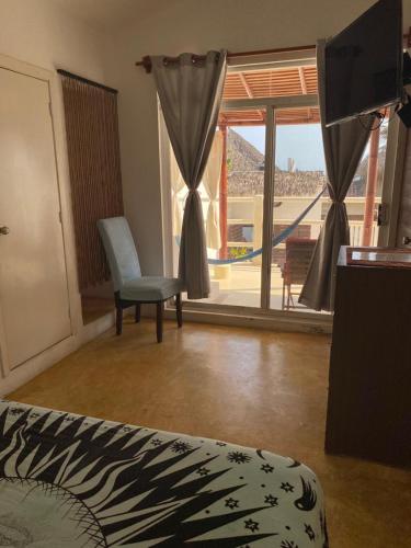 a room with a bed and a chair and a window at Casa de las Olas Surf & Beach Club in Acapulco