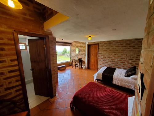 a bedroom with two beds and a brick wall at Balcon al Cotopaxi Hosteria in Sangolquí