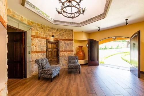 a living room with two chairs and a chandelier at Villa El Retiro Luxury Property in Alajuela City