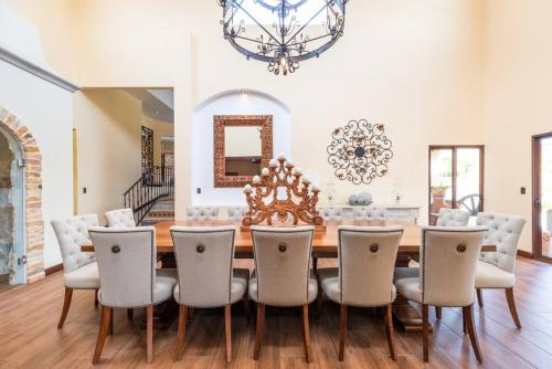 a dining room with a table and chairs and a chandelier at Villa El Retiro Luxury Property in Alajuela City