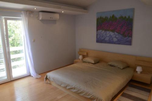 a bedroom with a bed and a painting on the wall at APARTMANI GOMILA in Jelsa