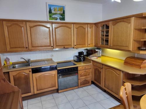 a kitchen with wooden cabinets and a stove top oven at Patkóház in Keszthely