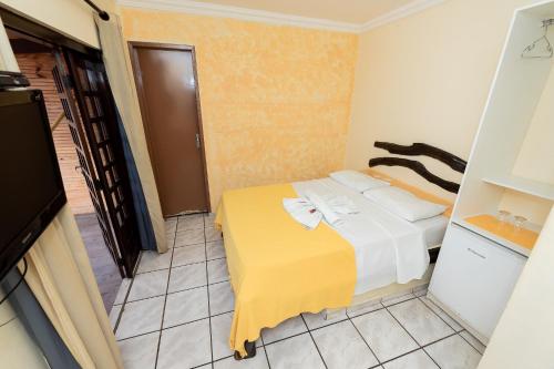 a bedroom with a bed with a yellow blanket at Pousada Terra do Sol Natal in Natal