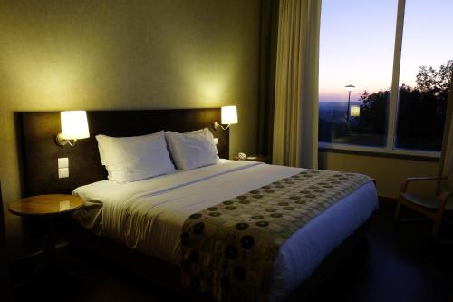 a bed in a hotel room with a large window at Hotel Da Montanha in Pedrógão Pequeno
