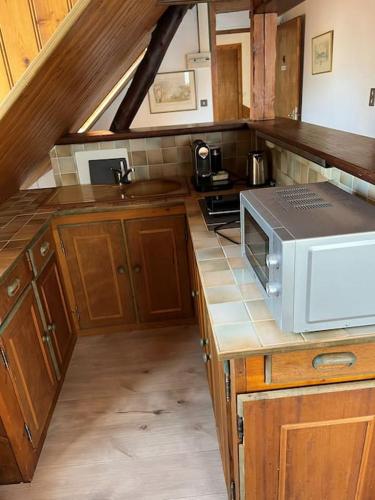 une cuisine avec des placards en bois et un four micro-ondes sur un comptoir dans l'établissement Top Floor Apartment with Mountain Views in the centre of Argeles Gazost, à Argelès-Gazost