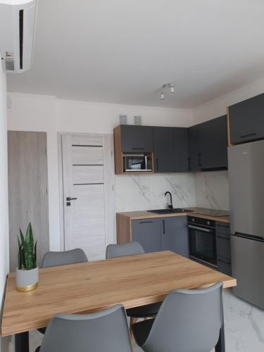 eine Küche mit einem Holztisch und Stühlen in der Unterkunft Mierzeja Park 13 apartament 40m2 in Sztutowo