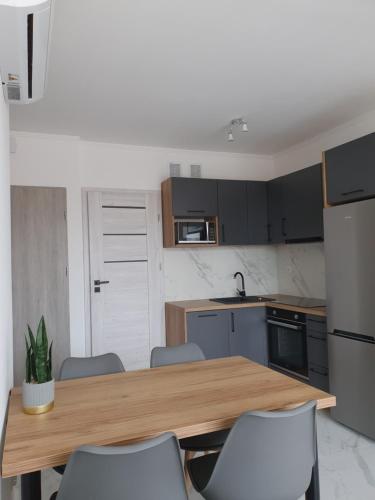 a kitchen with a wooden table and chairs at Mierzeja Park 13 apartament 40m2 in Sztutowo