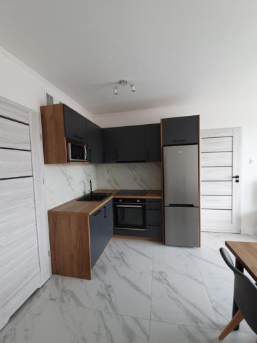 a kitchen with black cabinets and a white tile floor at Mierzeja Park 13 apartament 40m2 in Sztutowo