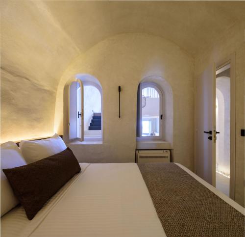 a bedroom with a large bed with two windows at Agnadema Apartments in Firostefani