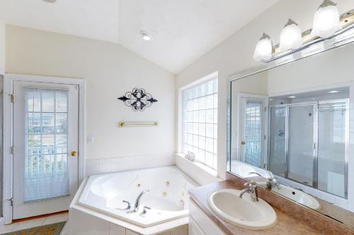 a bathroom with a tub and a sink and a mirror at A Slice of Paradise in Virginia Beach