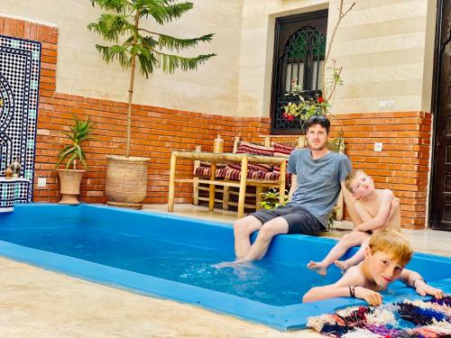 un homme et deux garçons assis dans une piscine dans l'établissement Riad 46, à Marrakech