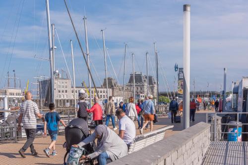 a group of people walking on a pier with boats at Sunny Sea Terkade in Ostend