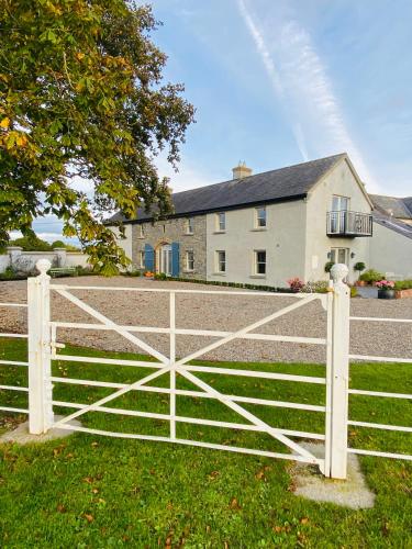 a white fence in front of a house at The Granary, Luxuriously Restored Barn on a Farm in Thurles